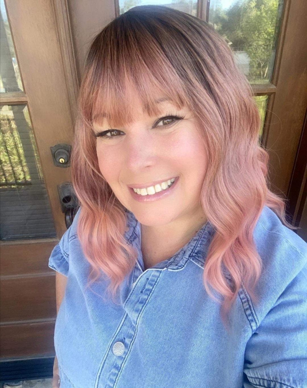 Short wavy pink synthetic wig with dark roots and bangs